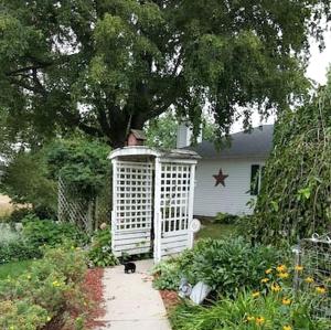 a white out house sitting in a garden at Comfortable Room Rental for a Vacation in Poweshiek County, Iowa in Montezuma