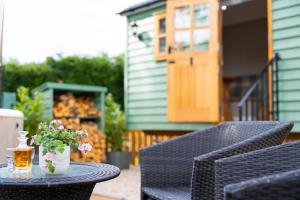 a table with a drink and flowers on a patio at Driftwood with Hot Tub in Corpach