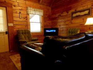 a living room with two leather couches and a television at Spacious Cabin Rental with a Hot Tub near the Gauley River in West Virginia in Hico
