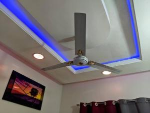 a ceiling fan with a blue light on a ceiling at 1 chambre salon a godomey in Ouéto