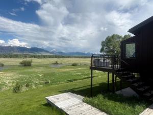 a deck of a house with a view of a field at Charming Riverfront Guest House with Deck Overlooking Madison River, Near Ennis, Montana in Ennis