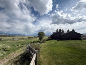 a fence in the middle of a field with a barn at Charming Riverfront Guest House with Deck Overlooking Madison River, Near Ennis, Montana in Ennis +25 photos