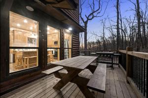 a wooden picnic table on a deck of a cabin at Beautiful Log Cabin with Private Hot Tub, Fire Pit, and Spacious Balcony, Perfect for a Luxury Mountain Retreat in Mount Herman