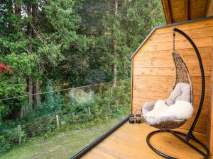 a swinging chair on a porch with a view of a forest at Chalet in Krimml near Zillertal Ski Arena in Krimml