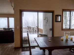 a living room with a wooden table and a balcony at Tree-House Style Cabin for Rent near Boone, North Carolina in Beech Mountain +10 photos