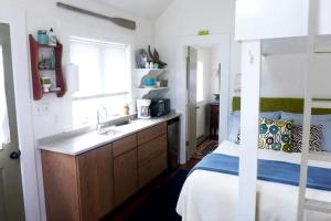 Una cocina con fregadero y una cama en una habitación. en Serene Tiny House with a Big Charm for Glamping in Virginia, en Accomac