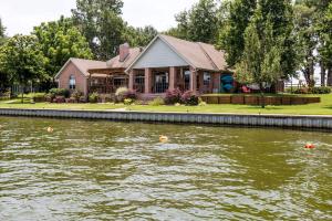 una casa seduta sul fianco di un fiume di Spacious Cottage Rental on the Shores of Cedar Creek Lake in Mabank, Texas a Enchanted Oaks