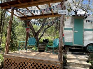 eine Veranda mit zwei Stühlen und ein Haus mit Flaggen in der Unterkunft Marble Falls Retro Caravan Glamping: Your Vintage Getaway Awaits in Marble Falls