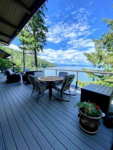 a deck with a table and chairs and a view of the water at Dog Friendly Cabin on Lake Pend O'reille with Hot Tub and Lakefront Views, Perfect for a Family Retreat on the Lake in Broten +39 photos