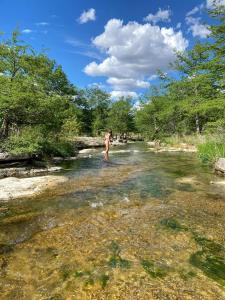 une personne debout dans l'eau d'une rivière dans l'établissement Beautiful Lakeside Rental with Hot-Tub in Igram, Texas, Perfect for Family Glamping Trips, à Hunt 59 autres photos