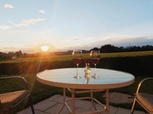two glasses of wine sitting on a table with the sunset at Ferienwohnung Trifts l Wallbox l Parkplatz l AusZeit Card in Wangen im Allgäu +40 photos