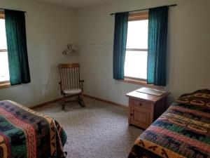 1 dormitorio con 1 cama, 1 silla y 2 ventanas en Simple Cabin Rental with Screened-In Porch on Moose Lake near Eau Claire, en New Post