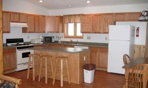 Una cocina con gabinetes de madera y un refrigerador blanco. en Simple Cabin Rental with Screened-In Porch on Moose Lake near Eau Claire, en New Post