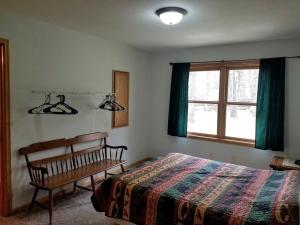 Un dormitorio con una cama y un banco y una ventana. en Simple Cabin Rental with Screened-In Porch on Moose Lake near Eau Claire, en New Post