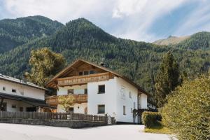 a building with a wooden roof with mountains in the background at Chalet-Midl in Umhausen
