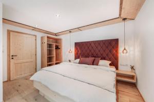 a bedroom with a large white bed with a red headboard at Chalet-Midl in Umhausen