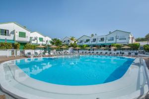 Una piscina en un resort con sillas y sombrillas. en Great Bungalow Maspalomas, en Maspalomas