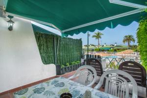 - Balcón con mesa y sillas y sombrilla verde en Great Bungalow Maspalomas, en Maspalomas