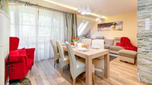 a dining room and living room with a table and red chairs at Wonder Home - Domki górskie z kominkami na kameralnym osiedlu - plac zabaw na terenie kompleksu in Karpacz