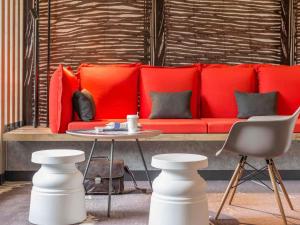 a red couch in a room with a table and chairs at ibis Nantes Centre Tour Bretagne in Nantes