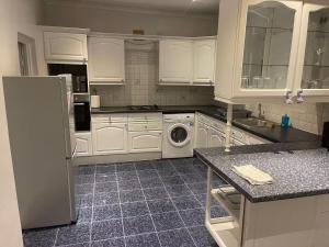 Una cocina con gabinetes blancos y lavadora. en Hendon Home, en Hendon 18 fotos más