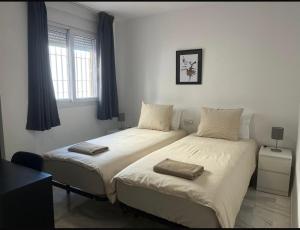 two beds in a bedroom with blue curtains at Spacious family friendly 3 bedroom home B' Pueblo - swimming pool - games room & sunny terrasse in Benalmádena +25 photos