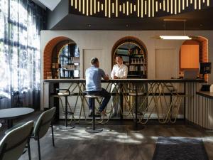 イシー・レ・ムリノーにあるibis Styles Paris Porte de Versailles - Mairie d'Issyの二人の男がレストランのバーに座っている