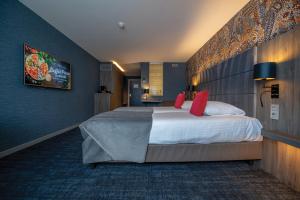 a hotel room with a large bed with red pillows at Van der Valk Hotel Liège Congres in Liège