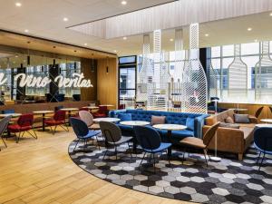 a restaurant with a blue couch and tables and chairs at ibis Paris CDG Airport in Roissy-en-France