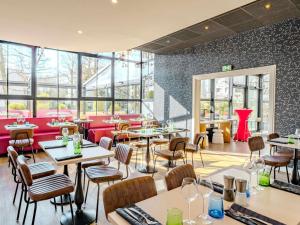 a restaurant with tables and chairs and windows at ibis Marne La Vallee Champs-sur-Marne in Champs-sur-Marne