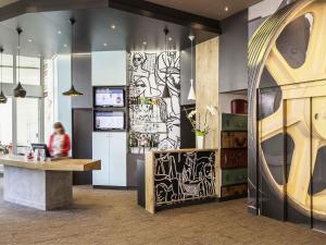 a lobby with a counter and a person in the background at ibis Poitiers Centre in Poitiers