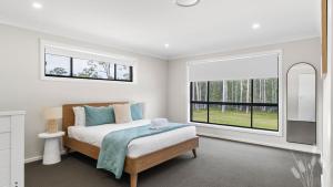 TomerongにあるModern Bush Retreat- Brand New 5BR Tranquil Escapeのベッドと窓のある寝室