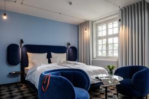 a bedroom with blue walls and a bed with blue chairs at Mintrops Stadt Hotel Margarethenhöhe in Essen