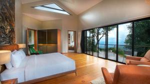 a bedroom with a white bed and large windows at Stanley Revelation in Attigundi