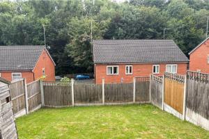 a fence in front of two houses with a yard at House - Sleeps 5 Private Parking & Pets Allowed in Manchester