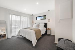 a white bedroom with a large bed and a window at Bellamy Station - Luxury on the Clutha Gold Trail in Evans Flat +17 photos