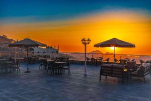 a patio with tables and chairs and umbrellas at sunset at Petra Legacy Luxury in Petra