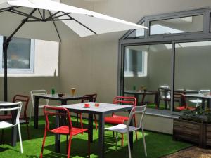 a patio with tables and chairs and a white umbrella at ibis Toulouse Centre in Toulouse