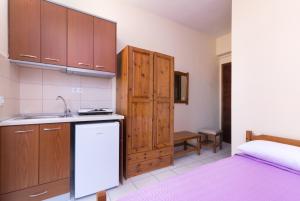 a kitchen with wooden cabinets and a sink and a bed at Studios Bridge in Limenaria