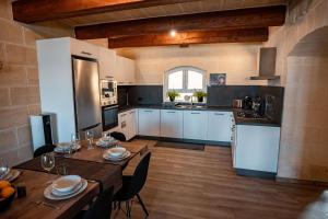 une cuisine avec parquet et armoires et tables blanches dans l'établissement Serena, à L-Għarb