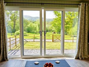 an open sliding glass door with a view of a yard at 1 Bed in Conwy 95098 in Llangelynin