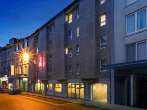 a tall brick building on a city street at night at ibis Leuven Centrum in Leuven