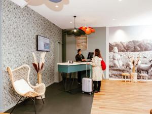 two people standing at a desk with their luggage at ibis Styles Luxembourg Centre Gare in Luxembourg