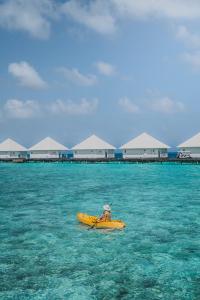 アスルガ島にあるDiamonds Athuruga Maldives Resort & Spaの海で黄色いカヤックに乗っている人