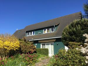 una casa con una puerta verde y un techo negro en Ferienwohnungen Reetwinkel in Wieck, en Wieck