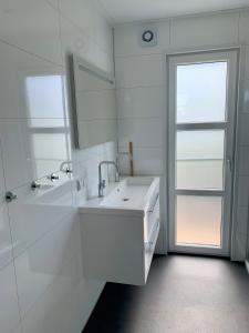 a white bathroom with a sink and a mirror at Marina Strandbad Chalet Sand & Seele Haus Nr 355 in Olburgen