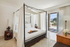 Un dormitorio con una cama con dosel con una bandeja de comida encima. en Mövenpick Resort & Residences Aqaba, en Áqaba