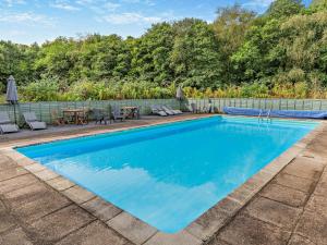 a swimming pool with a patio and a table and chairs at 3 Bed in Saltash 30040 in Landrake