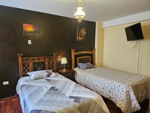 a bedroom with two beds and a flat screen tv at El Seminario Hospedaje in Cajamarca