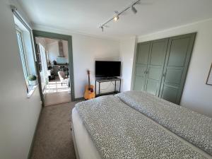 a bedroom with a bed and a television and a guitar at Guest wing at Ginkelösa Nygården in Linköping